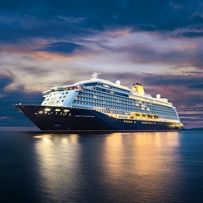 Spirit of Adventure illuminated, sailing against a twilight sky